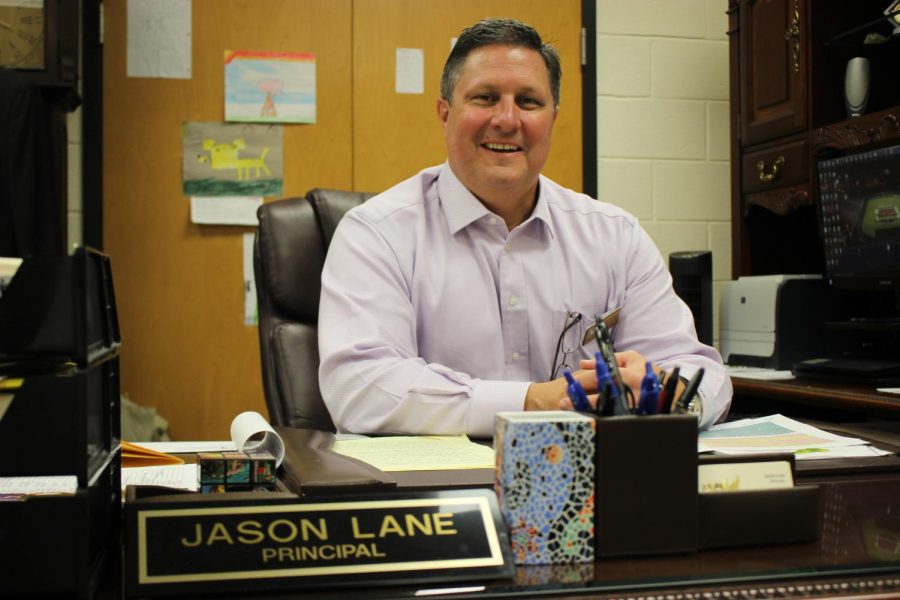 Greg Cantrell sitting at Principal Jason Lanes desk in Lanes office.