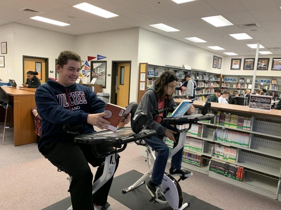 Students+Cade+Jones%2C+9%2C+and+Matthew+Willis%2C+9%2C+reading+books+while+riding+bikes+in+the+media+center