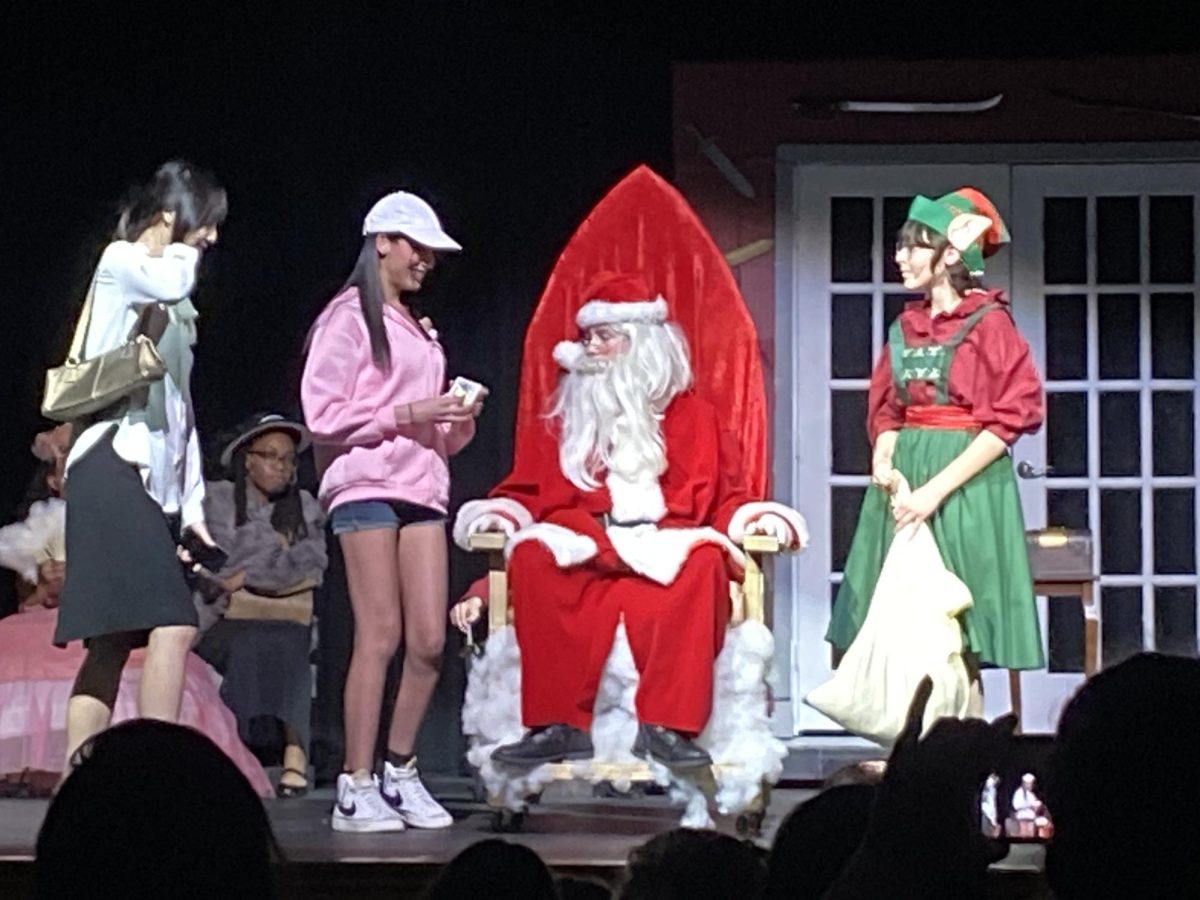 Santa Claus, played by Josh Hodges,9, the Elf, played by Camila Cook, 9, in a flashback scene as a Mall Santa. 